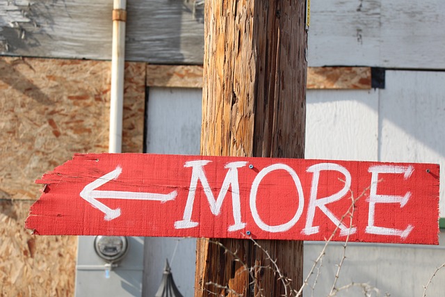 Red sign reading MORE nailed to a wooden post